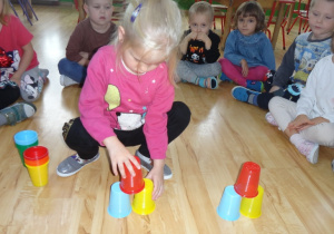 Dziewczynka układa kolorowe kubki